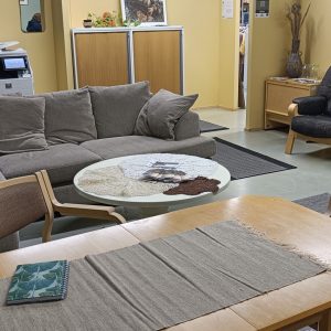 Työnhakutupa huonekaluineen, sohva, pöytä ja nojatuoleja.